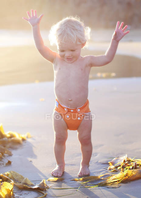 Toddler on beach holding arms in air — Stock Photo