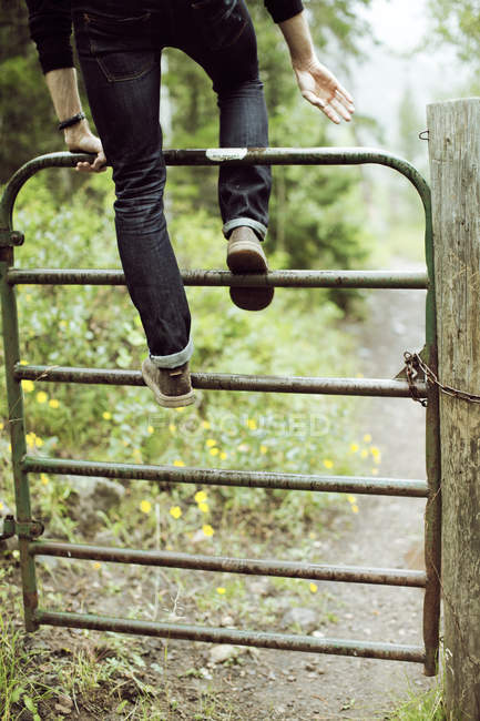 Homme grimpant la barrière — Photo de stock