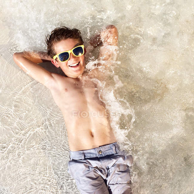 Улыбающийся мальчик лежит в море — стоковое фото