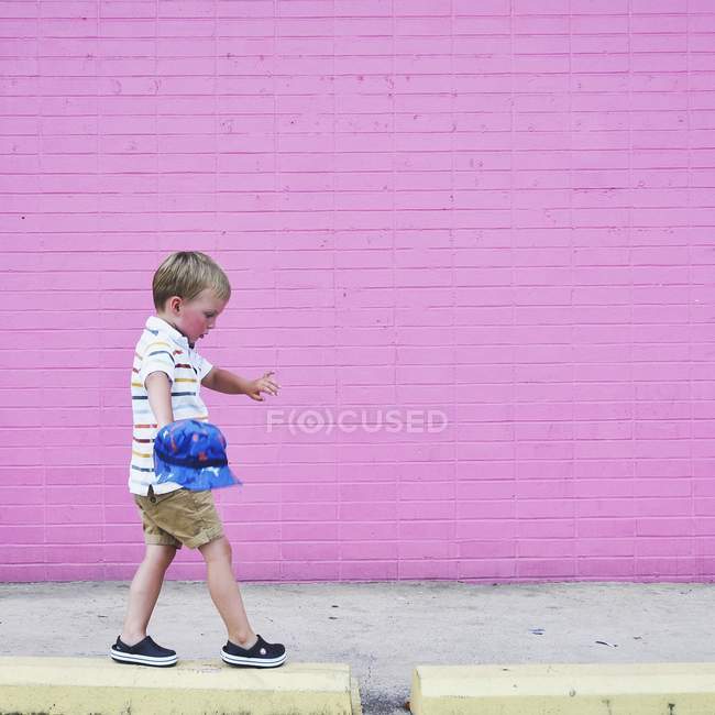 Garçon marchant sur le trottoir surélevé — Photo de stock
