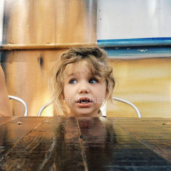 Chica sentada en la mesa - foto de stock