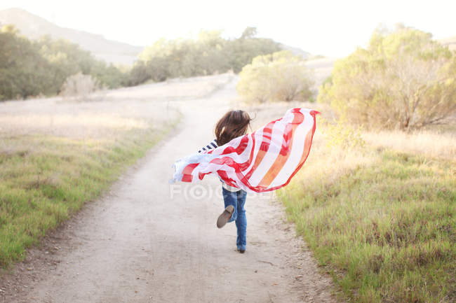 Девушка бежит по тропинке с американским флагом — стоковое фото