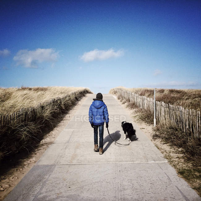 Мальчик гуляет с собакой — стоковое фото