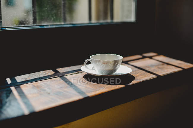 Cup of coffee beside window — Stock Photo