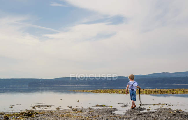 Мальчик идет вдоль озера — стоковое фото