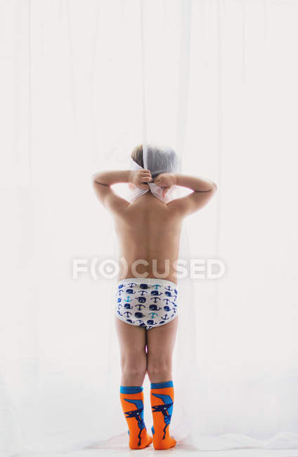 Boy in underpants looking at window — Stock Photo