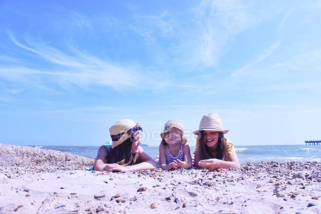 Три девушки, лежащие на пляже — стоковое фото