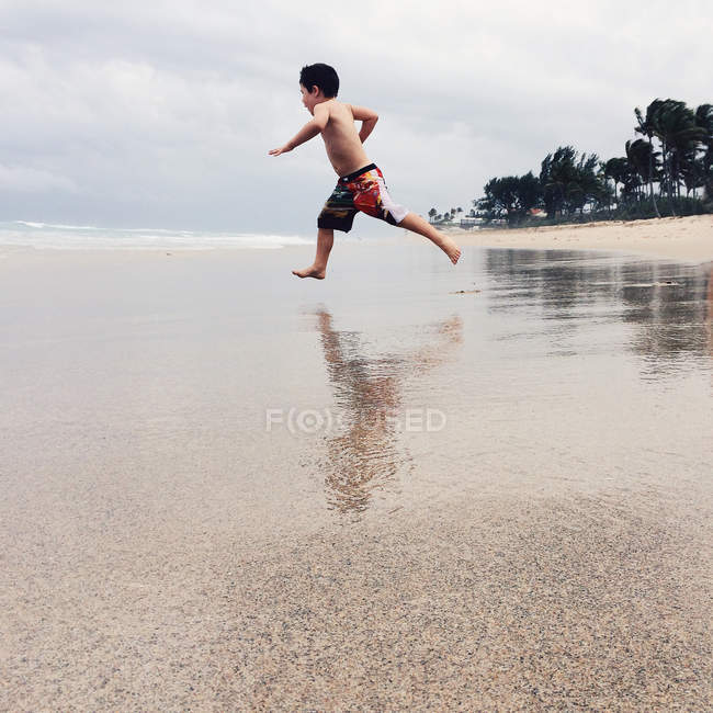 Niño corriendo en la playa - foto de stock
