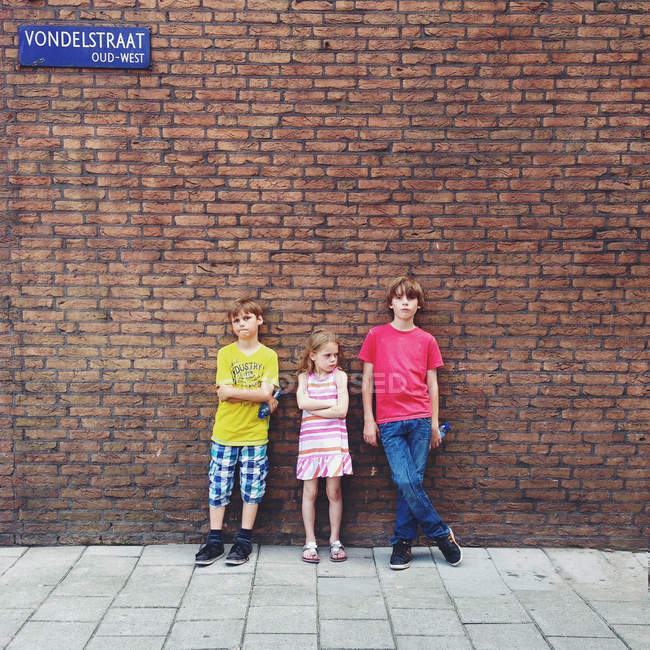 Children standing in front of brick wall — Stock Photo