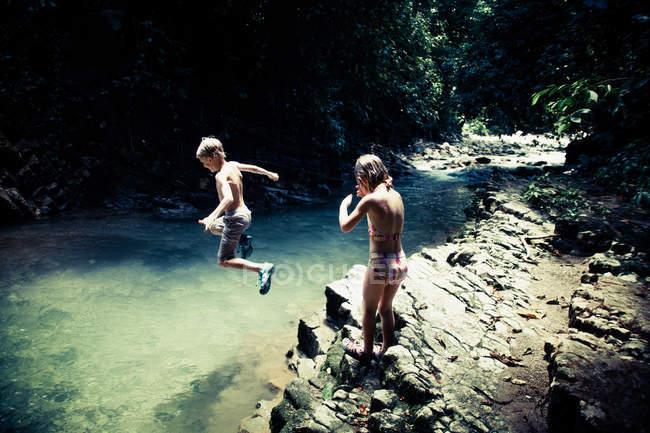 Niño y niña divirtiéndose por el río - foto de stock