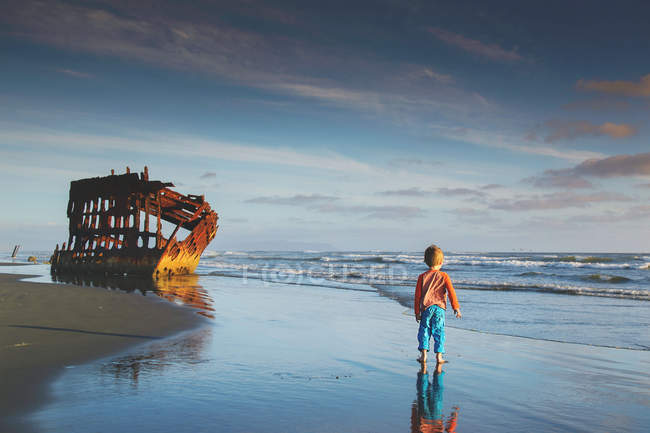 Rapaz a caminhar em direcção ao naufrágio — Fotografia de Stock