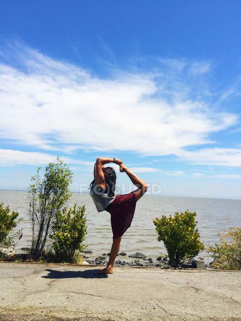 Девушка практикует йогу на море — стоковое фото