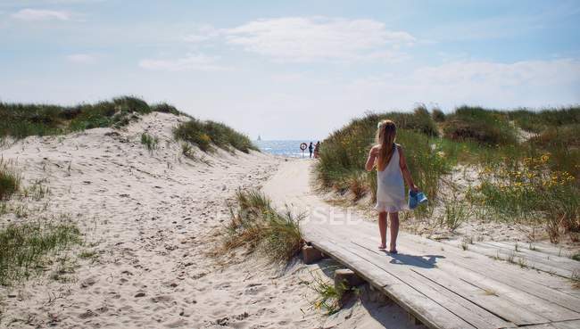 Girl walking on path towards sea — Stock Photo