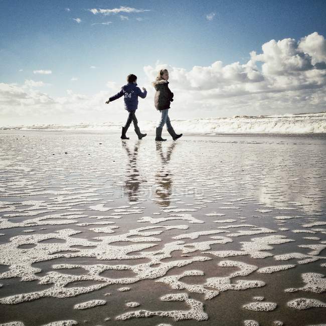 Bambini che camminano lungo la spiaggia — Foto stock
