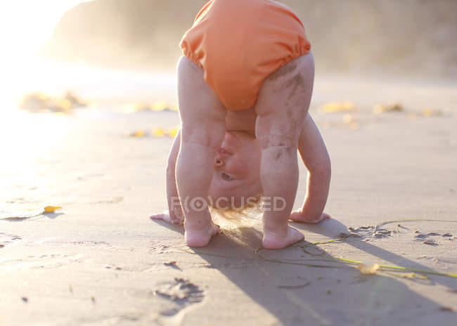 Тоддлер наклоняется на пляже — стоковое фото
