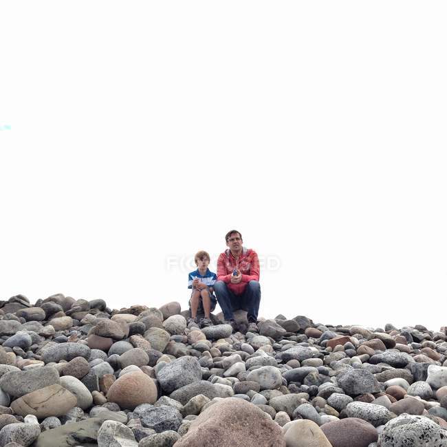 Pai e filho sentados em rochas — Fotografia de Stock