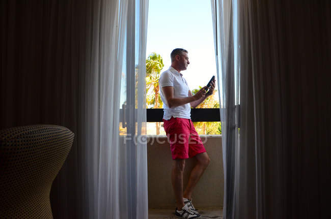 Человек с цифровым планшетом на балконе — стоковое фото