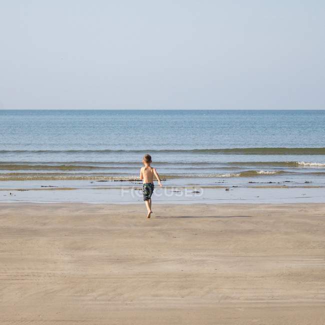Хлопчик біжить у море — стокове фото