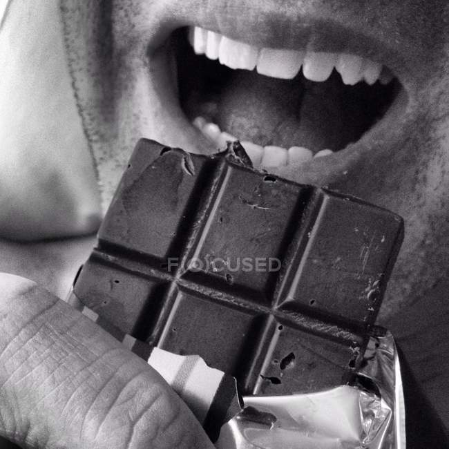 Hombre comiendo barra de chocolate - foto de stock