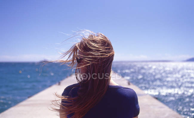 Woman with blowing hair on quay pier — Stock Photo