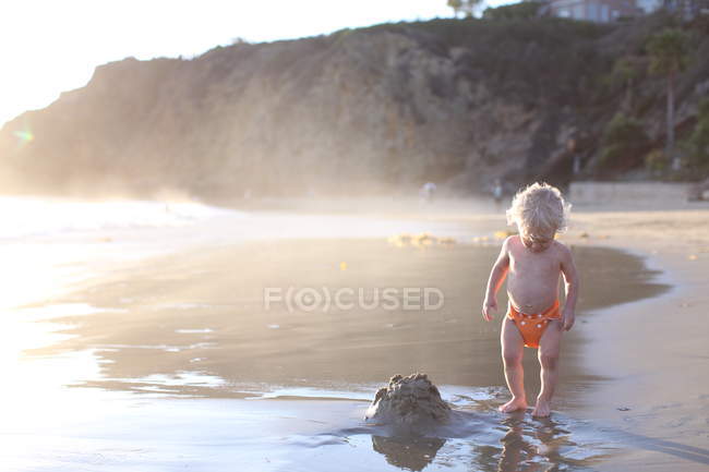 Niño de pie en la playa - foto de stock