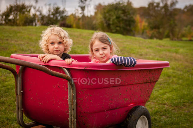Two girls sitting in wheelbarrow — Stock Photo
