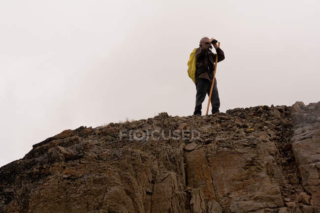 Homme âgé avec jumelles sur la montagne — Photo de stock