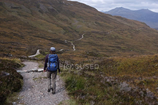 Woman walking along mountain trail — Stock Photo