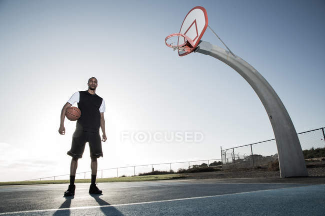 Uomo che tiene palla da basket nel parco — Foto stock