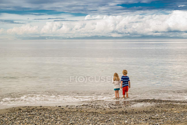 Mädchen und Junge stehen am Strand — Stockfoto