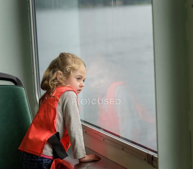 Girl looking out of window on boat — Stock Photo