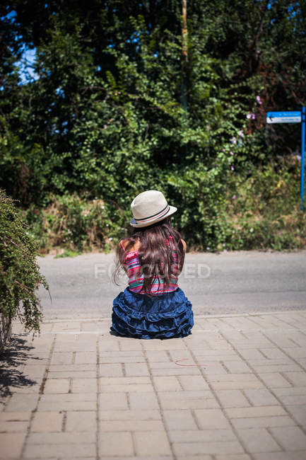 Дівчина сидить на тротуарі — стокове фото
