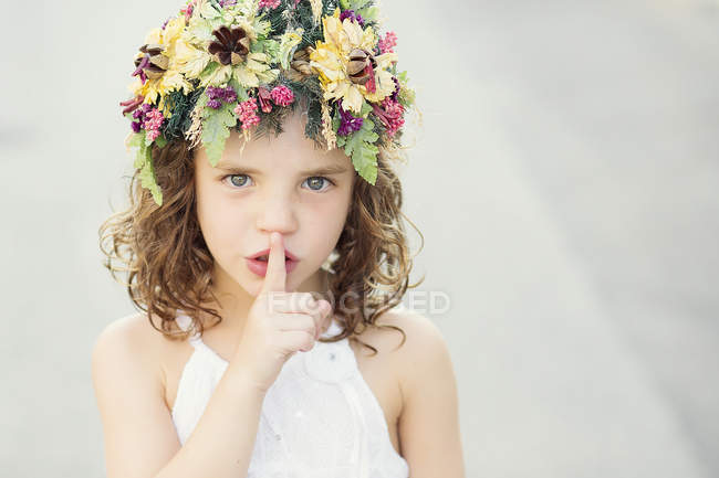 Chica sosteniendo el dedo delante de la boca - foto de stock