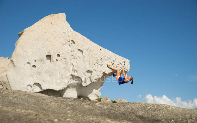 Молодая женщина карабкается на большой камень — стоковое фото