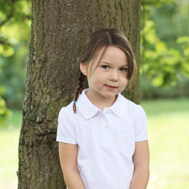 Chica de pie junto al árbol - foto de stock