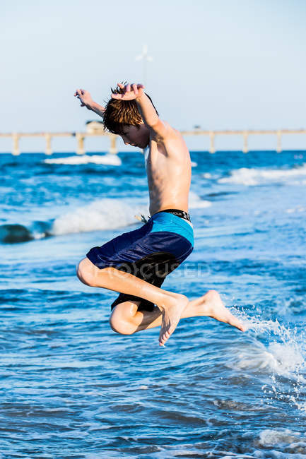 Red haired boy jumping into surf — Stock Photo
