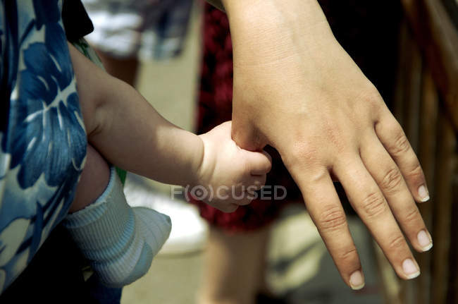 Bébé fils tenant la main mère — Photo de stock