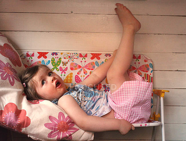 Girl raising legs while lying on sofa — Stock Photo