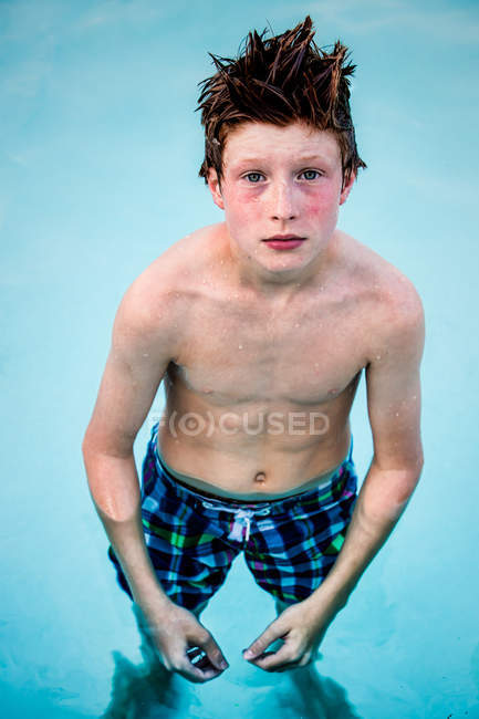 Garçon debout dans la piscine et levant les yeux — Photo de stock