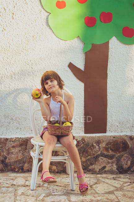 Ragazza seduta sulla sedia con le mele — Foto stock