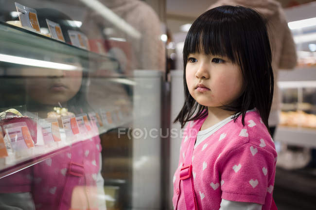Mädchen schaut auf Schaufenster im Geschäft — Stockfoto