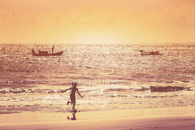 Chica corriendo en la playa durante el atardecer - foto de stock