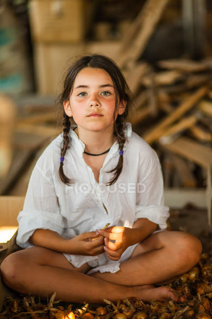 Дівчина з косами сидить на землі — стокове фото