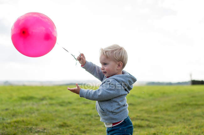 Niño con globo rosa - foto de stock