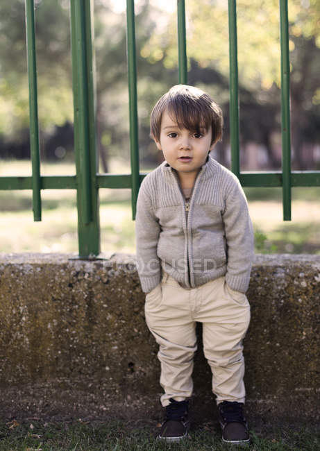 Мальчик, стоящий за школьным забором — стоковое фото
