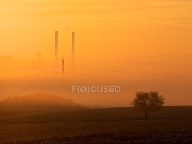 Camini della centrale elettrica nella nebbia arancione — Foto stock
