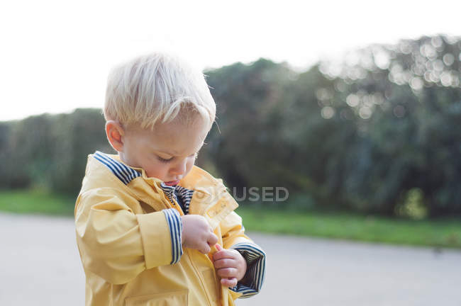 Мальчик застегивает пальто — стоковое фото