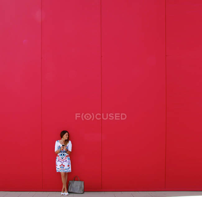Mujer de pie frente a la pared roja - foto de stock
