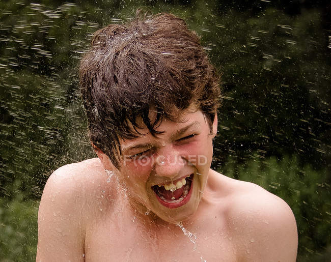 Rapaz a ser salpicado com água — Fotografia de Stock