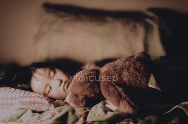 Chica durmiendo con osito de peluche - foto de stock